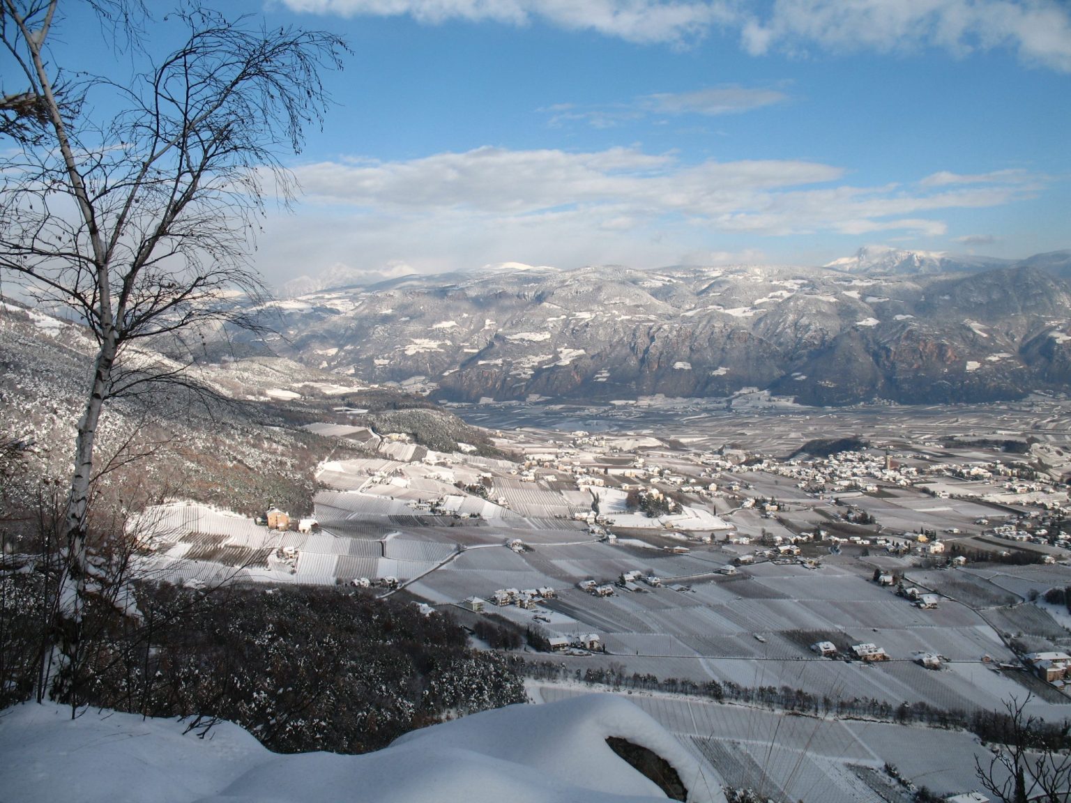 Ausblick auf das verschneite Überetsch mit Eppan Berg im Vordergrund und den Weinort St. Pauls dahinter
